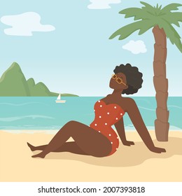 Young black-skin woman is enjoying hot summer day and sitting on the beach near the sea