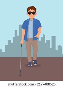 Young blind man in dark glasses walking with a cane stick on the street