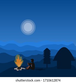 Young boy sitting in front of camp fire in the cool breeze on mountains during night near his hut with tree behind and with beautiful mountains view