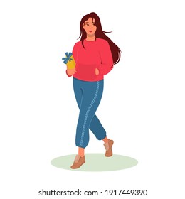 a young brunette woman is walking with a yellow gift box in her hands. the concept of buying gifts for the holiday