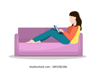 young brunette woman working on laptop lying on sofa. Concept of working from home and freelancing