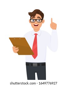 Young  business man in eye glasses holding clipboard and pointing finger up. Trendy person keeping notepad, document, folder or report. Male character gesturing hand. Idea! Vector cartoon illustration