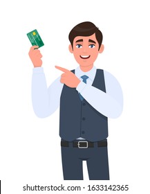 Young business man showing credit, debit card and pointing finger hand. Trendy person in waistcoat holding ATM card. Stylish male character illustration. Modern lifestyle design in vector cartoon.