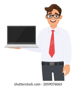 Young Business Man Showing A New Laptop. Person Carrying A Latest Computer (PC). Male Character Holding Digital Technology Device. Modern Lifestyle Concept Design Illustration In Vector Cartoon Style.