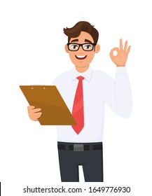 Young Businessman Holding Clipboard And Showing Okay Or OK Sign With Fingers. Trendy Person Keeping Notepad, Document Or Folder. Male Gesturing Good Or Agree. Cartoon Illustration In Vector Style.