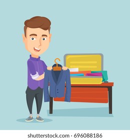 Young businessman packing his clothes in an opened suitcase. Smiling caucasian businessman putting a suit into a suitcase. Man preparing for vacation. Vector flat design illustration. Square layout.