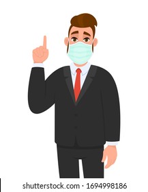 Young businessman wearing medical mask and pointing finger up symbol. Trendy hipster person covering face protection and gesturing hand sign. Male character cartoon illustration in vector style.