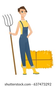 Young caucasian farmer in overalls standing with a pitchfork on the background of hay bales. Full length of farmer holding a pitchfork. Vector flat design illustration isolated on white background.