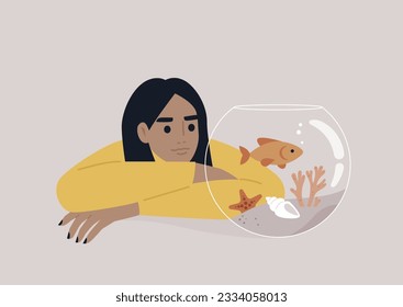 A young Caucasian person watching a goldfish swimming in a round water tank