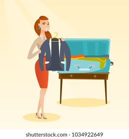 Young caucasian white woman packing her clothes in an opened suitcase. Smiling woman putting a jacket into a suitcase. Cheerful woman preparing for vacation. Vector cartoon illustration. Square layout