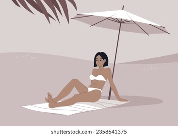 A young Caucasian woman relaxes on the sandy shore beneath a white beach umbrella, enjoying her summer getaway amidst the sweltering tropical heat