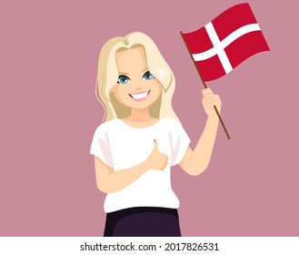 Young cheerful Danish woman with long blonde hair holding Denmark flag in casual clothes showing thumb up