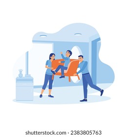 A young and cheerful husband and wife moved the armchair occupied by their son into the house. A small family moves to a new home. A couple of happy, funny parents concepts.