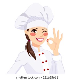 Young confident chef woman in uniform winking one eye and gesturing ok sign with her hand