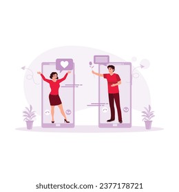 A young couple appears from a mobile phone screen, making an online call. Online Dating concept. Trend Modern vector flat illustration