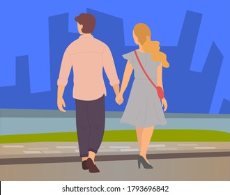 Young couple, back view, blond girl and guy in brown trousers, walk in evening city. River, skyscrapers, buildings background. Happy people hold hands and smile. Outdoor activities, open air walking