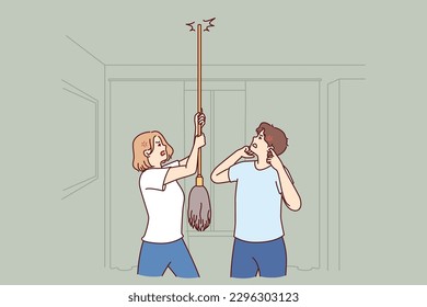 Young couple bangs on ceiling with mop urging neighbors to stop party or turn off loud music. Angry men and women use mop suffer from noisy neighbors not respecting rules of living together