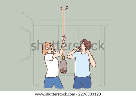 Young couple bangs on ceiling with mop urging neighbors to stop party or turn off loud music. Angry men and women use mop suffer from noisy neighbors not respecting rules of living together