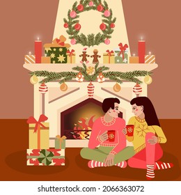 young couple dressed in bright sweaters and socks with coffee mugs, sitting together by the fireplace the winter holidays. Christmas Couple. Happy Smiling Family at home celebrating. New Year People