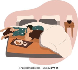 Young couple in love happily having breakfast with croissants and coffee on mattress at home enjoying romantic moment