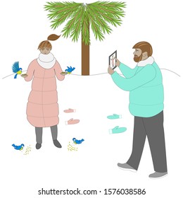 Young couple outdoor. Girl is feeding birds anp man is making her photo.