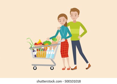 Young couple pushing a shopping cart full of groceries.
