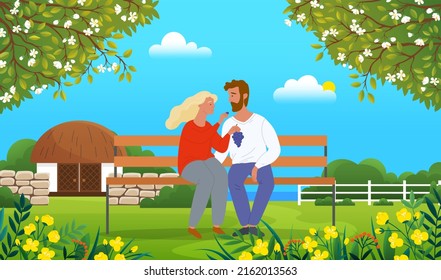 Young couple relaxing at bench in park. Girl holding grape and feeding boyfriend with berries. Happy in love people spending time together outdoors at nature. Relationship, joint pastime concept