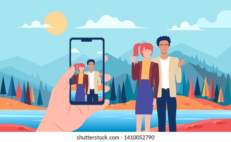 Young couple taking picture by mobile phone on the background of nature beautiful mountains view