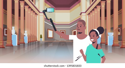 young couple using selfie stick taking photo on smartphone camera african american man woman visitors in modern art gallery museum hall interior portrait horizontal