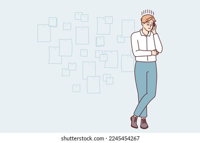 Young creative man project manager stands cross-legged and touches head thinking about future development of company. Startup employee guy posing near wall with stickers. Flat vector illustration
