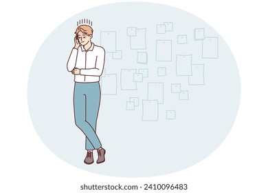 Young creative man project manager stands cross-legged and touches head thinking about future development of company. Startup employee guy posing near wall with stickers. Flat vector illustration