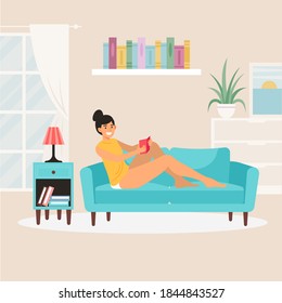 Young cute tanned woman reading in her sofa.