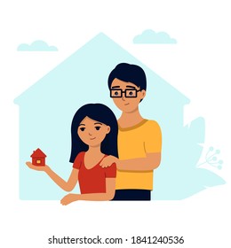 A young family buys a house , a woman holds a house in the palm of her hand and smiles, a man puts his hand on his shoulder as a sign of support .