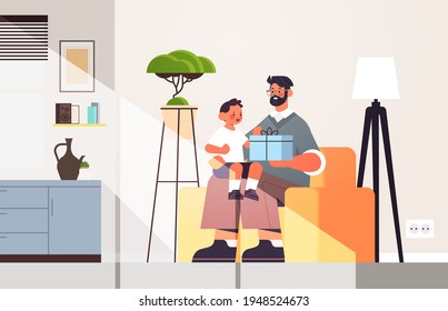 young father holding gift box for son parenting fatherhood concept dad giving holiday present to his kid at home