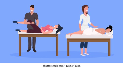 young female clients enjoying traditional massage man woman masseurs in coat massaging patients lying on bed luxury spa and wellness center concept horizontal full length blue background