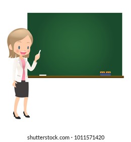 The young female teacher dressed in the suit stands before a blackboard with chalk