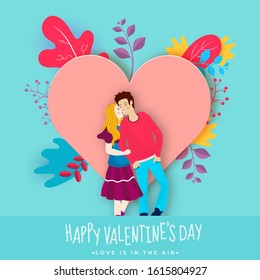 Young Girl kissing her Boyfriend with Paper Cut Blank Heart Decorated Colorful Leaves on Turquoise Color Background for Happy Valentine's Day Celebration.