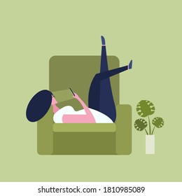 Young girl lying on a sofa with her legs in upward position and looking at the smart phone