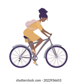 Young girl rides a bicycle in a dress and with a backpack. A student or schoolgirl goes to class. Woman cyclist riding a bicycle