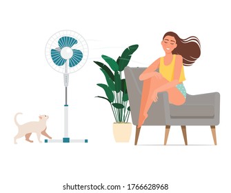 A young girl sits in an armchair and her hair flutters from the wind of a fan on a hot day.