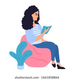 A young girl sits in a chair bag and reads a paper book. Student preparing for the exam. Literature fans. Love reading.