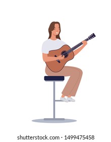 Young girl sitting on the chair, playing acoustic guitar