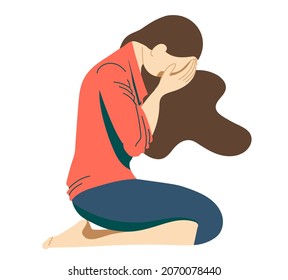 Young girl, a teenager suffering from psychological illnesses, depression, anxiety, is sitting on the floor with her face covered with her hands and her head lowered