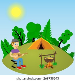 Young guy with a guitar in a forest glade near the fire and tent