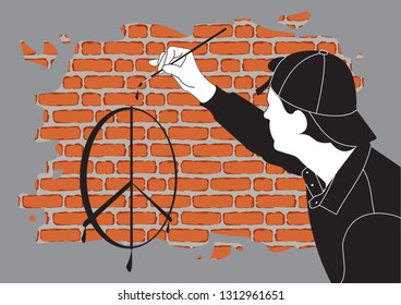 A young guy painter in the cap draws signs on the brick wall