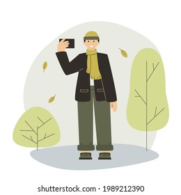 Young guy takes a selfie on autumn background. Flat fall concept for web, site, app. Vector young blogger in the autumn city park. A guy takes a photo against the background of autumn trees.