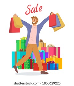 Young handsome happy guy picks up multi-colored packages. Male character with shopping bags in his hands. Big gift boxes on the background. Holliday sale concept. Preparation for the celebration