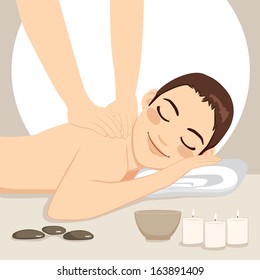 Young handsome man getting relaxing massage treatment lying down on bed at spa with soft light candles and Zen elements