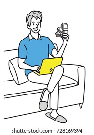 Young handsome man, sitting on sofa at home with computer laptop, holding pile of money banknotes in hand, in concept of working at home, freelancer. 