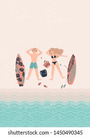 young happy couple man and woman blonde lie on the beach and relax next to their surfboards. Surfers